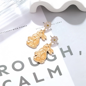 Detail of cute enamel rabbit earrings with floral stud on a clean white background