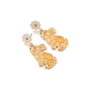 Detailed macro of bunny earrings with orange enamel texture and white daisy studs