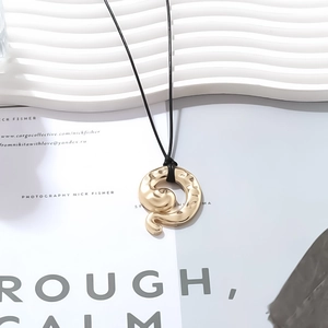 Detail of vintage gold alloy snake pendant with irregular texture on black cord