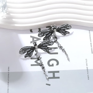 Detail of dragonfly earrings featuring silver-tone metal and shimmering pearls
