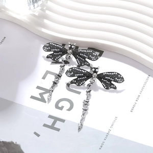 Retro silver dragonfly drop earrings with white beads and rhinestone accents on white board