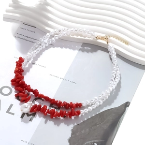 Collier double rang avec perles et pierres rouges sur fond décoratif blanc