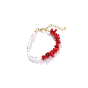 Détail d'un collier fait main avec perles baroques blanches et pierres rouges