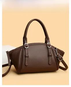 Détail d'un sac à main marron avec motif litchi, finitions argentées et doubles anses