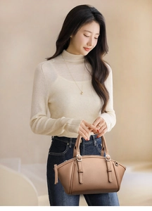 Sac à main marron en cuir grainé avec boucles argentées porté par un mannequin élégant