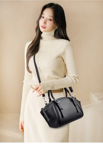 Détail d'un sac à main en cuir grainé noir avec doubles poignées et bandoulière