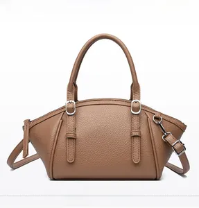 Gros plan sur le cuir grainé marron et les boucles argentées de ce sac à main