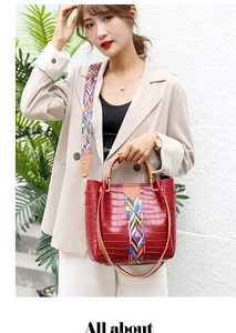 Detail of burgundy crocodile pattern bucket bag with wide geometric woven shoulder strap