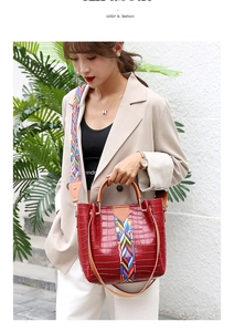 Detail of red crocodile texture handbag with colorful ethnic style woven wide strap