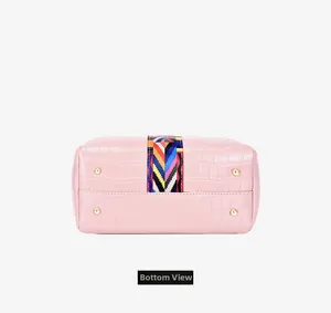 Detailed bottom view of pink crocodile textured bucket bag with golden protective metal feet