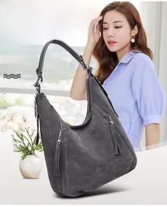 Detailed view of dark grey frosted suede shoulder bag with dual tassel zipper accents