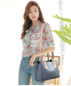 Borsa tote in pelle blu navy abbinata a camicia a fiori e jeans in stile casual