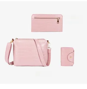 Detailed view of pink crocodile-embossed bag set including crossbody bag and wallets
