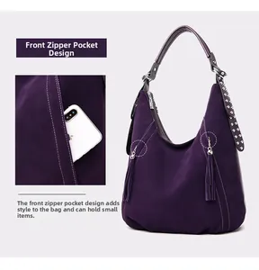 Detail of deep purple matte shoulder bag showing tassel charm and front zipper pocket