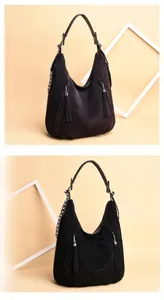 Detail view of vintage matte shoulder bag featuring metal rivets and tassel pendants