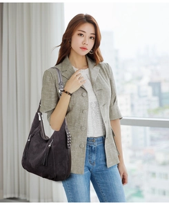 Detail of grey frosted leather shoulder bag with side tassels and silver studs decoration