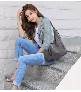 Detail of dark grey hobo bag with fringe zipper and soft matte texture on stone stairs