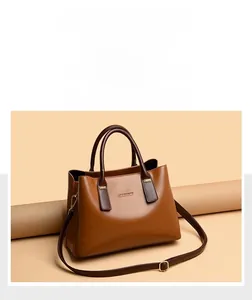 Dettaglio della borsa tote in pelle marrone con logo metallico e tracolla robusta