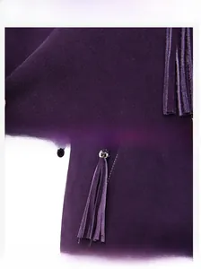 Detailed view of dark purple suede fabric with decorative tassels and precision stitching