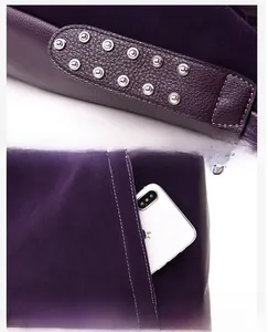 Detail of silver rivets on dark purple leather shoulder bag and functional front zipper pocket