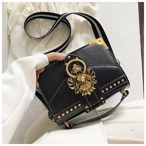 Detail der schwarzen Ledertasche mit goldenem Löwenkopfbügel und Metallnieten