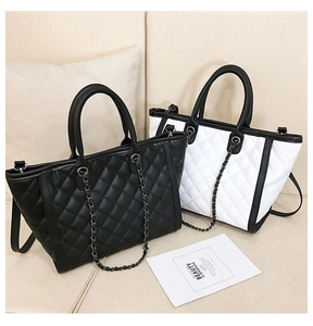 Détail de sacs cabas en cuir matelassé noir et blanc avec bandoulières en chaîne