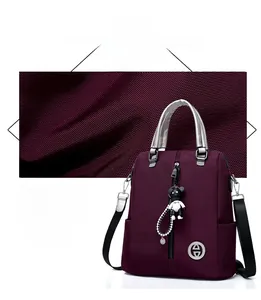 Détail du sac à dos imperméable violet foncé avec poignées argentées et breloque ours
