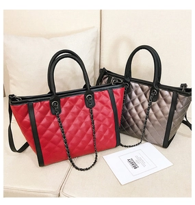 Détail des sacs cabas matelassés rouges et gris avec bandoulières sur canapé blanc