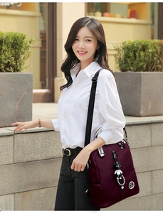 Détail d'un sac à dos en nylon bordeaux avec zips argentés et porte-clés panda mignon