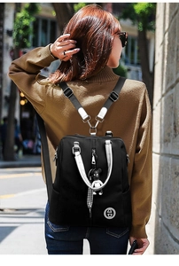 Détail du sac à dos en nylon noir avec fermeture éclair argentée et pendentif damier