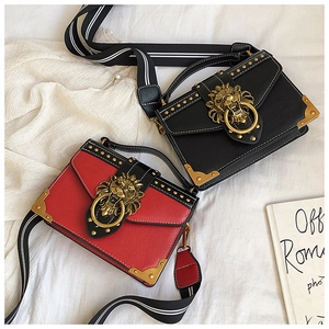 Detailansicht roter und schwarzer Lederhandtaschen mit goldener Löwenschnalle und Nieten