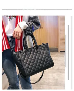 Détail du sac cabas matelassé noir avec chaîne et texture en cuir sur modèle