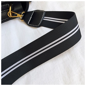 Detail eines schwarzen breiten Nylon-Schultergurts mit weißen Streifen und Goldhaken