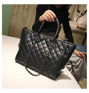 Détail d'un cabas noir matelassé avec surpiqûres en losanges et poignées à chaîne chic