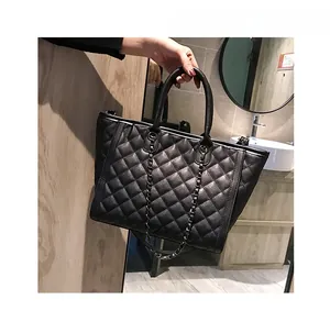 Détail d'un sac cabas en cuir noir matelassé avec bandoulière chaîne et poignées