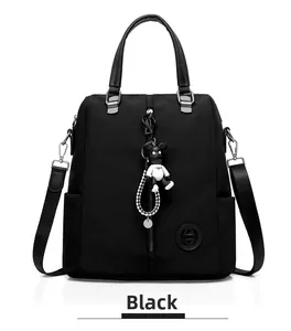 Détail d'un sac à dos noir en nylon avec fermeture éclair décorative et pendentif ours