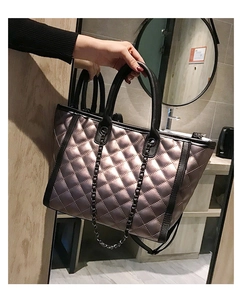Détail d'un sac cabas matelassé bronze avec poignée en cuir noir et chaîne en métal
