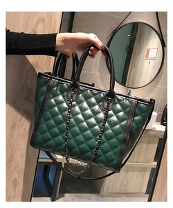 Détail du sac cabas matelassé vert foncé avec bordure en cuir noir et poignée chaîne