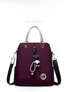 Vue avant du sac à dos en nylon violet foncé avec charm ours en peluche et poignée argentée