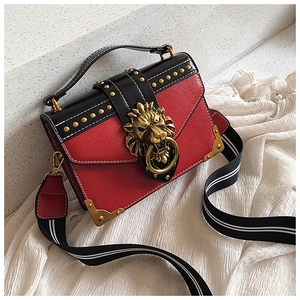 Detailaufnahme der roten Tasche mit goldenem Löwenkopf-Verschluss und Metall-Nieten