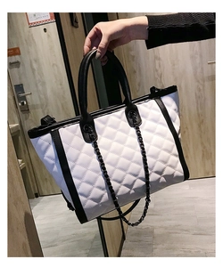Détail du sac cabas blanc matelassé avec poignées noires et bandoulière en chaîne métal