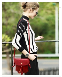 Détail d'un sac bandoulière rouge en similicuir avec pompon et boucle dorée