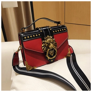 Detail der roten und schwarzen Ledertasche mit goldener Löwenkopfschnalle und Nieten