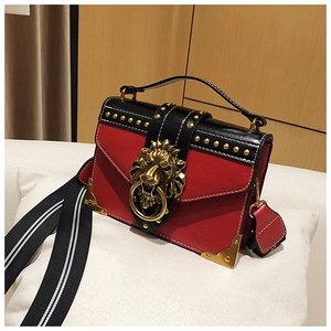 Detail der goldenen Löwenkopfschnalle und Nieten an der Kontrast-Lederhandtasche