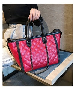 Détail du sac cabas matelassé rouge avec poignées noires et décoration de chaîne
