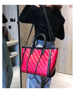 Sac fourre-tout rouge matelassé avec bordure noire porté par un mannequin chic