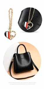 Dettaglio di una borsa in pelle martellata nera con ciondolo a cuore in smalto colorato