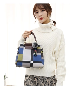 Detail of color-block tote bag with plush pompom charm and logo ribbon decoration