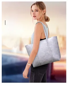 Photo de rue d'un grand sac cabas en cuir gris porté à l'épaule par un mannequin dehors