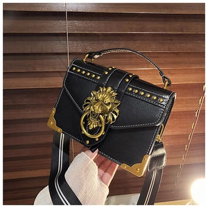 Detail der schwarzen Ledertasche mit goldenem Löwenkopfverschluss und Nietendekor